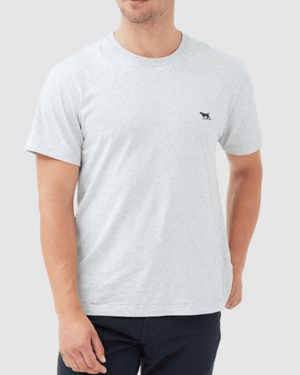 A man wearing the Rodd & Gunn The Gunn T-Shirt in light grey Australian cotton, featuring a small dark animal logo on the left chest, paired with dark pants and standing against a plain light background.