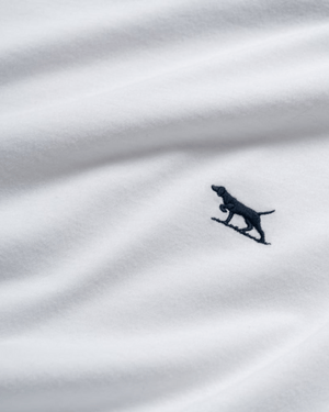 Close-up of soft Australian Cotton fabric from Rodd & Gunn The Gunn T-Shirt, featuring a small embroidered black dog logo. The gentle folds highlight its quality construction and sports fit appeal.