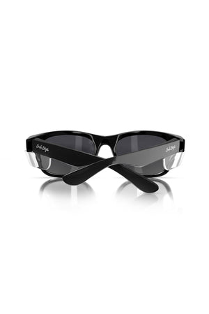 A pair of SafeStyle Classics Black Frame Tinted Lens sunglasses featuring a sleek design, dark tinted lenses, and black arms with transparent hinge accents. The folded sunglasses show the arms crossed over each other, revealing white signature text on the temples against a plain white background.