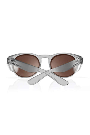 The SafeStyle Cruisers feature transparent gray polycarbonate frames, brown polarised lenses, and an oval shape. Shown from the back with crossed arms.