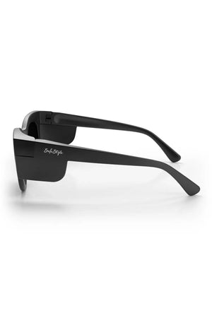 The SafeStyle Harps Matte Black Frame Polarised Lens sunglasses are shown from the side with thick frames and temples. "SoStyle" is printed in white on the left arm near the hinge. Features UV protection and a plain white background.