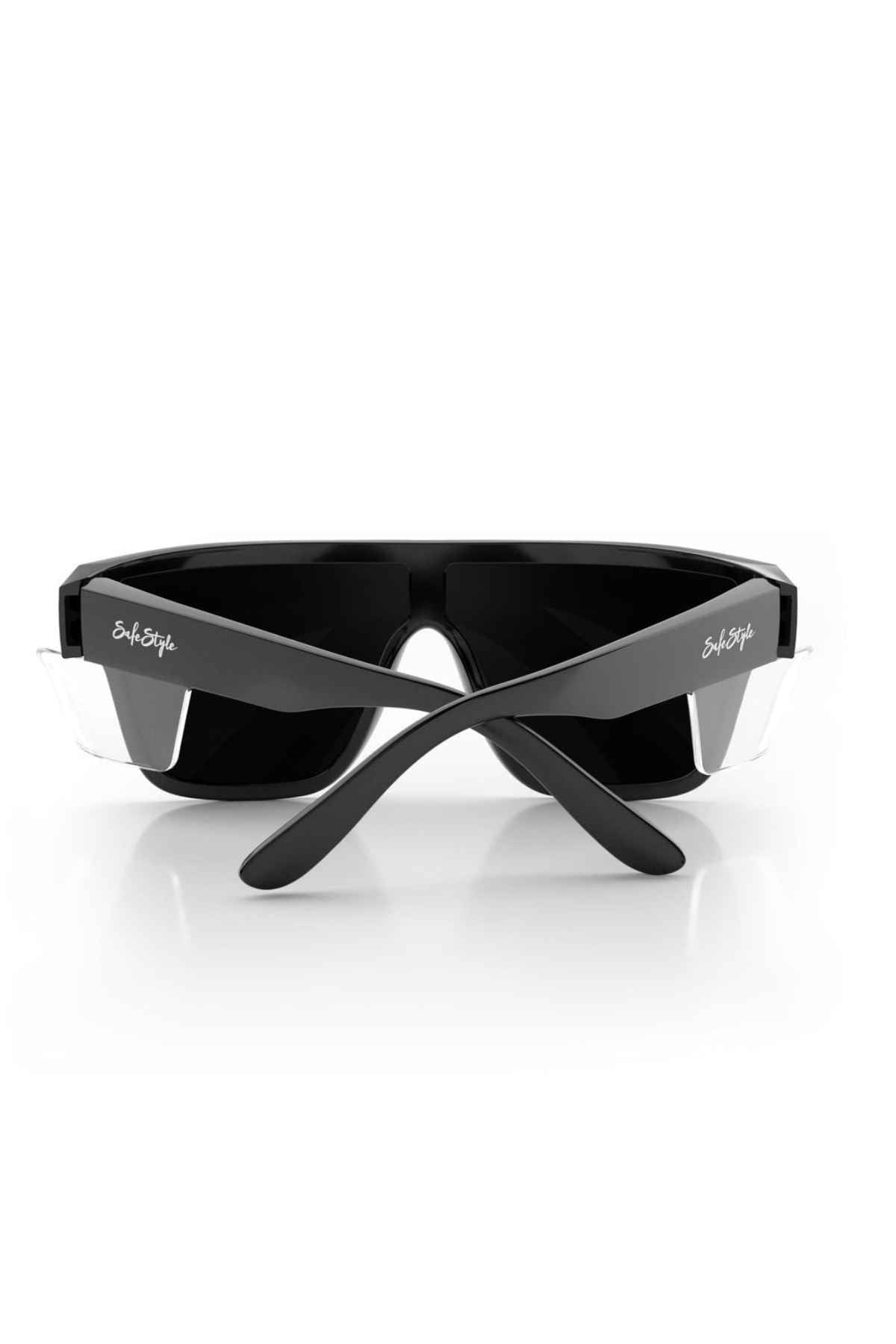 A pair of sleek black sports sunglasses, named SafeStyle Primes Black Frame Polarised Lens, with white text on the temples, displayed on a plain white background. The arms are crossed at the hinges, and the dark lenses offer Polarised UV400 protection. Crafted from shatterproof polycarbonate, these oversized style sunglasses are designed for high performance.