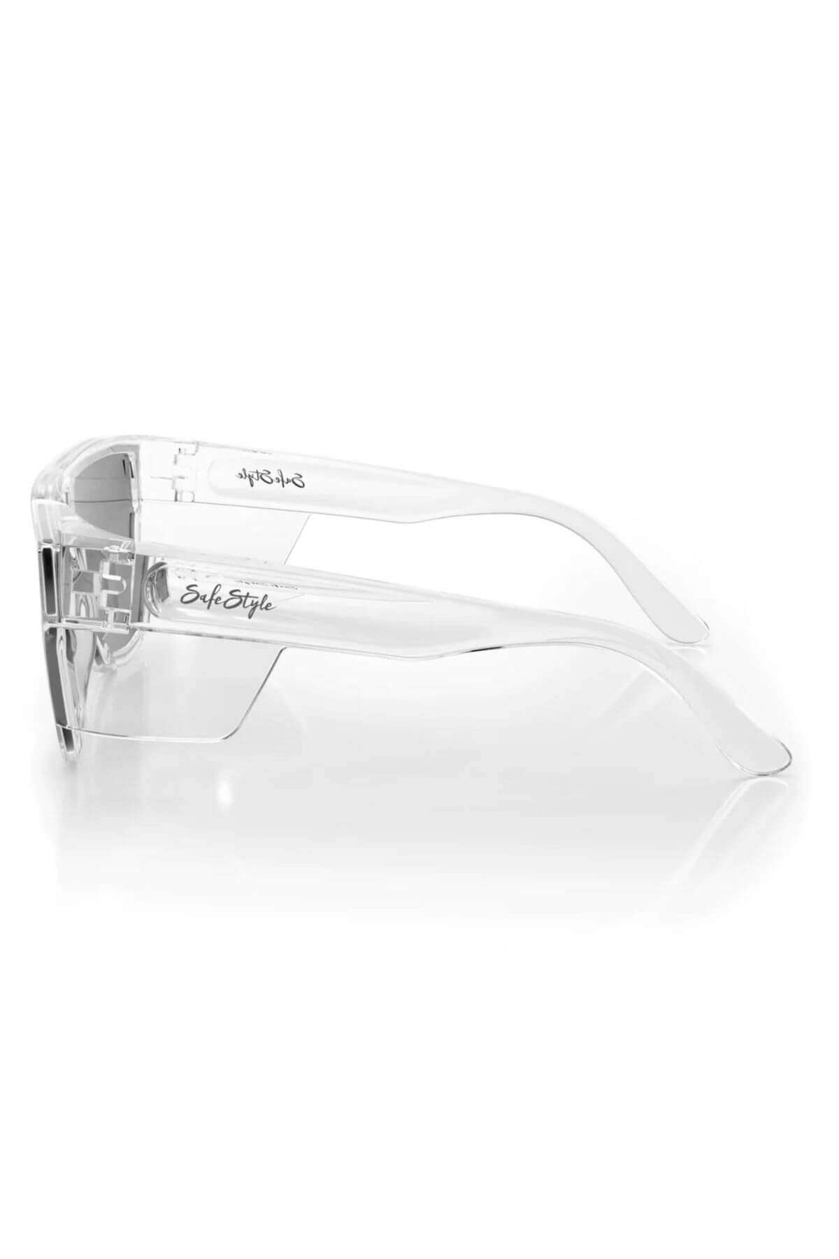 The SafeStyle Primes glasses feature clear frames, tinted wrap-around lenses with an antiscratch coating, and "SafeStyle" printed on the temple arms. These sleek safety glasses rest elegantly on a reflective white surface.