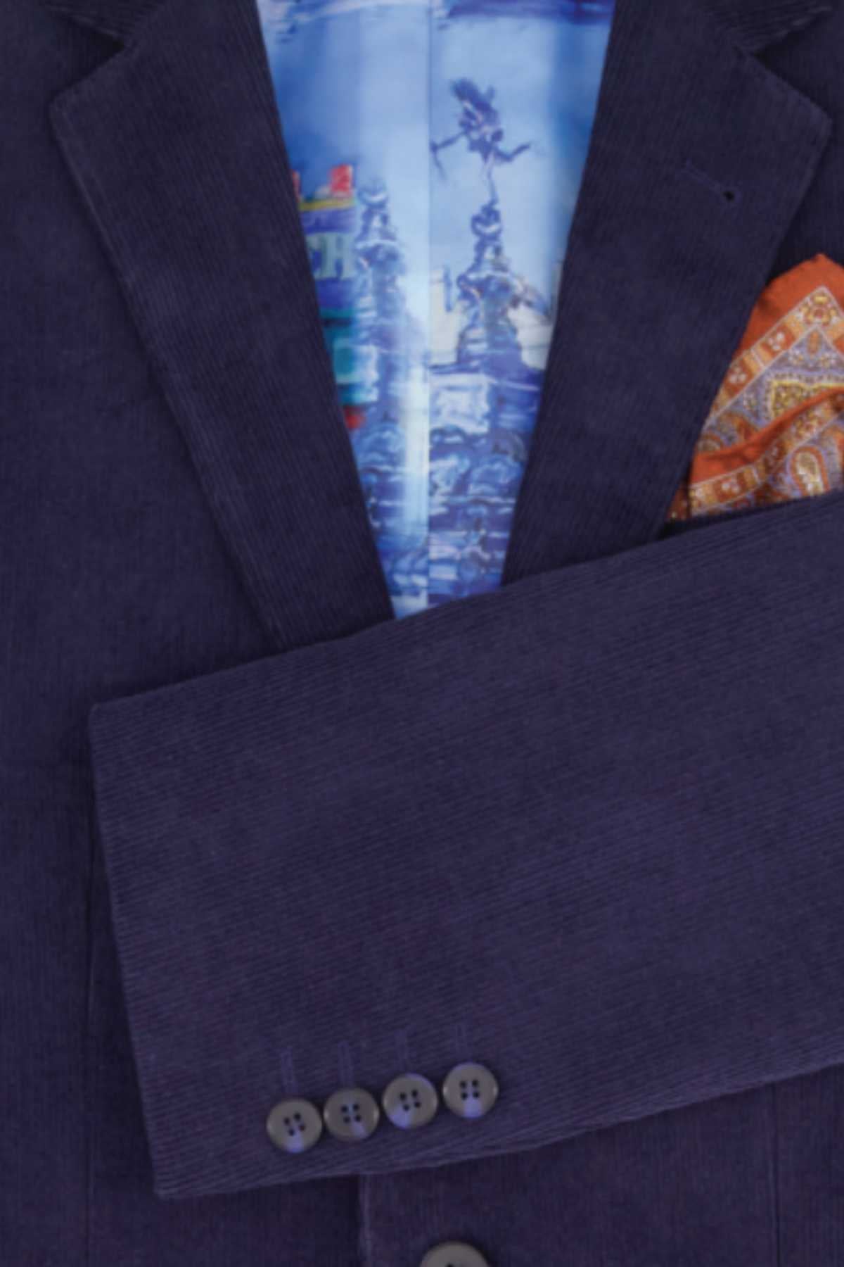 Close-up of the Savile Row Abram Corduroy Jacket in dark blue, featuring four sleeve buttons, a vibrant printed lining, and an orange patterned pocket square in the chest pocket.