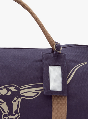 Close-up of the RM Williams Nanga Canvas Bag, a dark cotton bag with brown handles, an exterior pocket, a steer head design, plus a tag holder near the zipper.