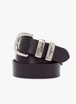 The RM Williams Slim Drover Belt, made of black solid hide leather, features a nickel buckle and an engraved silver plate with "R.M.Williams" and a longhorn logo, coiled neatly on a plain white background.