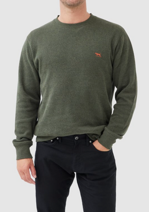 The man dons a Rodd & Gunn Gunn Crew Neck Sweat in olive green, made from 100% cotton, highlighting a small orange animal logo on the chest. He pairs it with black pants against a plain white background.