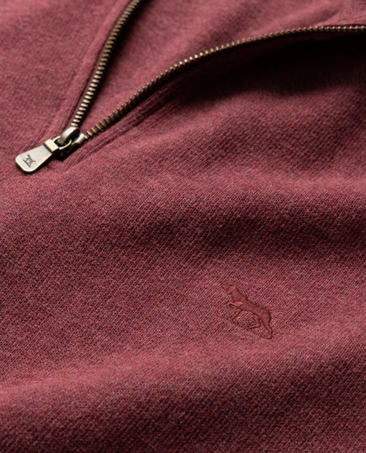 Close-up of the Rodd & Gunn Alton Ave Sweat in maroon, highlighting a quarter zip with a metal zipper. Made from 100% cotton, it features an embroidered animal logo that subtly decorates the texture.