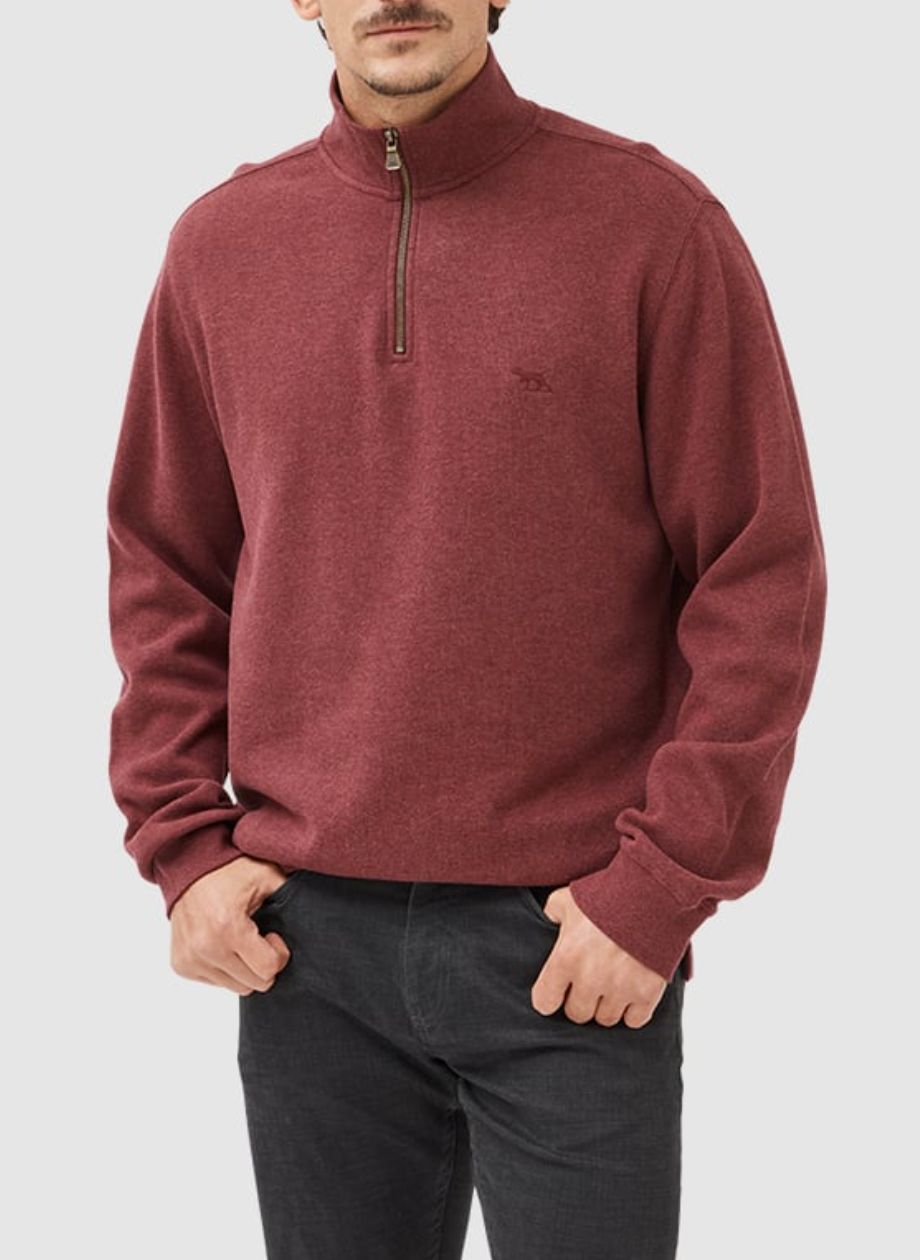 A person stands with hands in pockets, wearing dark pants and the maroon Rodd & Gunn Alton Ave Sweat, a 100% cotton quarter-zip pullover featuring a subtle logo on the left chest, set against an off-white backdrop.