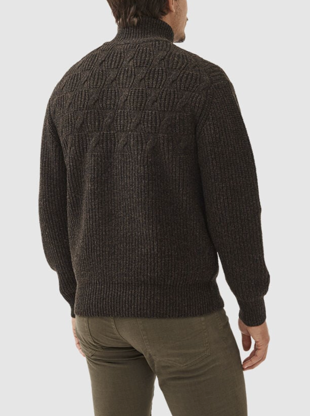 A person is seen from behind wearing the Rodd & Gunn Challis Knit, an olive green lambswool sweater with a high collar and ribbed cuffs, paired with matching olive green pants.