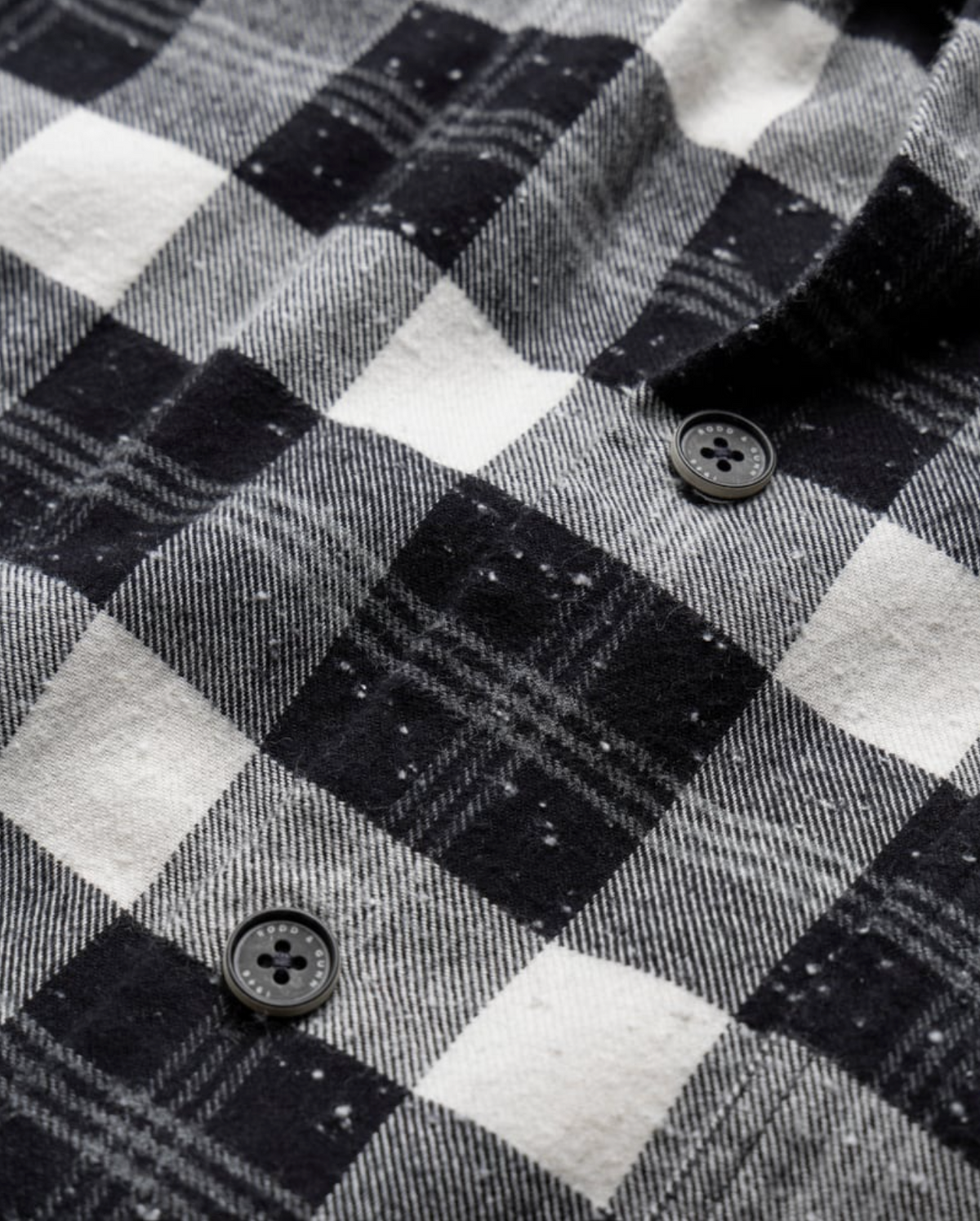 Close-up of the Rodd & Gunn Halfmoon Ave Shirt, a comfortable 100% cotton checkered flannel with two black buttons. The soft, textured fabric displays detailed stitching and subtle color variation in the pattern.