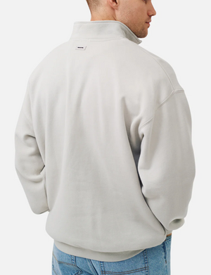A man is shown from the back, hands in pockets, wearing the Industrie The Del Sur Track Top in light grey with a high collar and soft fleece lining, paired with blue jeans against a plain white background.