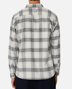 A person wears the Industrie The Silverton Shirt, a stylish, regular-fit flannel with a white and gray plaid pattern, viewed from the back. Its long sleeves enhance its relaxed charm, and it's slightly loose-fitting. They're also donning dark pants.