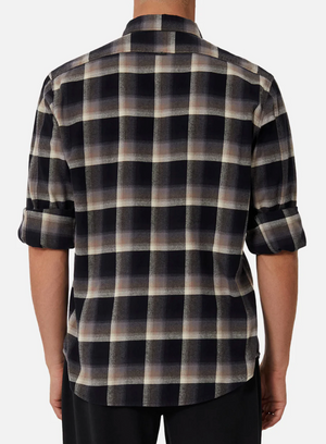 Someone is wearing the Industrie The Clifton Shirt, a long-sleeved, regular fit plaid with black, white, and brown colors made of 100% cotton. The sleeves are rolled up, the shirt is untucked, and only the back is visible.