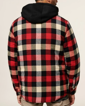 A person is standing with their back to the camera, wearing a red, black, and white checkered Hard Yakka Quilted Flannelette Shacket with a black hood. The person is also wearing beige pants. This durable shacket style features buttons on the cuffs.