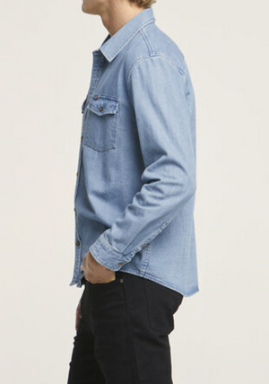 A person in a Wrangler Roadside Denim Shirt made of 100% cotton and black pants is shown in profile against a plain background, highlighting their upper body.