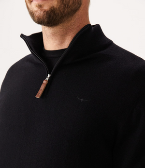 A bearded man wearing the black RM Williams Ernest Sweater, featuring a 1/4 zip with leather pull tab and a subtle longhorn logo on the chest, is shown from the shoulders up against a plain background.