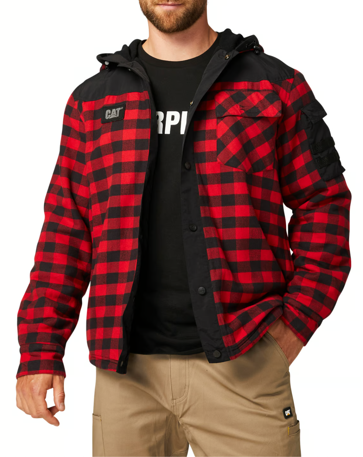 A person wears the CAT Sequoia Shirt Jacket, featuring a red and black plaid design with fleece lining and a hood, over a black T-shirt. The cotton jacket includes buttons and chest pockets and is paired with beige pants. The head is not visible in the image.