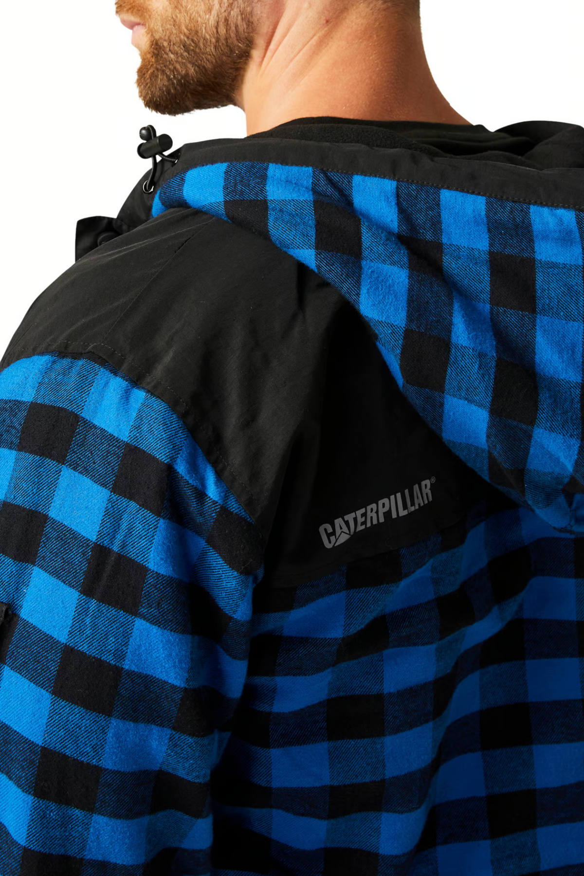 A close-up of a person wearing the CAT Sequoia Shirt Jacket, featuring a blue and black checkered pattern, fleece-lined hood, cozy design, and the Caterpillar logo on the back.