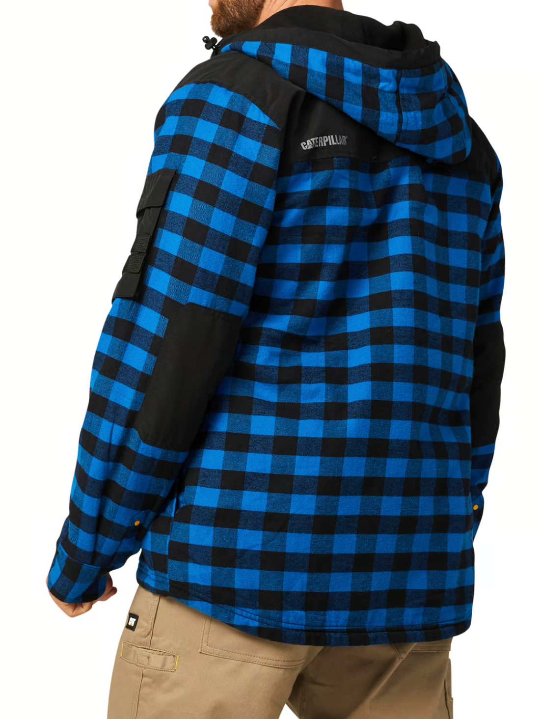 A person wearing a CAT Sequoia Shirt Jacket in blue and black check, featuring durable shoulder and sleeve overlays, with tan pants. The person's back faces the camera.