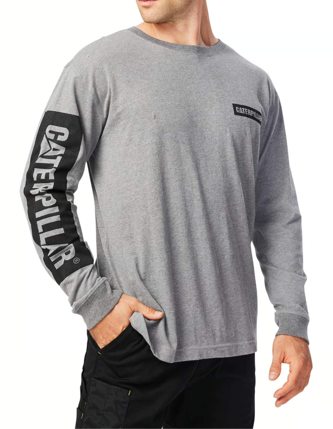 A person is wearing a gray CAT Icon Block Long Sleeve Tee, featuring black text on the sleeve and a small chest logo. Made from 100% cotton, they stand with one hand in their pants pocket, shown from shoulders to hips.