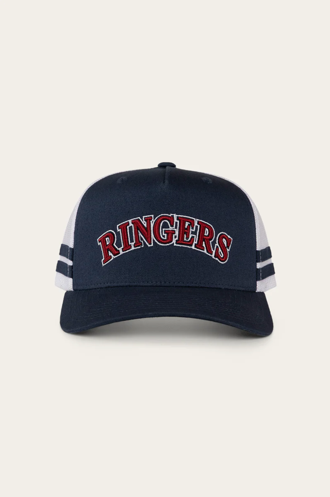 The Ringers Western Caleb Trucker Cap features navy and white colors, "RINGERS" embroidered in red and white on the front, two navy stripes on each side of the white mesh panels, and is made from durable cotton twill for comfort and style.