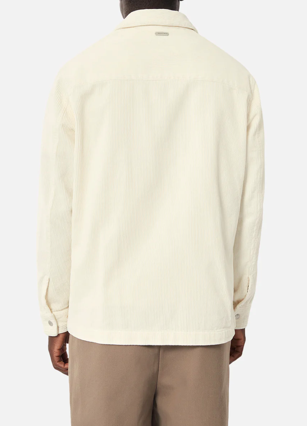 A person is seen from the back wearing Industrie The Atmore Jacket, a stylish cream corduroy piece with detailed corduroy accents. It's made of 100% cotton, featuring a collar, buttoned cuffs, and relaxed fit, paired with brown pants against a plain white background.