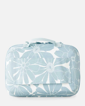 The Rip Curl Paradise F-Light Beauty Case is light blue with white floral patterns, a top handle, a large front pocket, and a rectangular shape. Made from soft recycled polyester fabric.