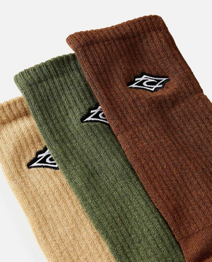 The Rip Curl Diamond Crew Sock 3 Pack, featuring arch support for comfort, includes three ribbed socks in beige, green, and brown with small embroidered logos. They are displayed side by side on a plain background.