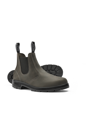 The Mongrel K9 Elastic Sided Boot K91085 in olive green features premium leather construction with black elastic side panels and pull tabs. It showcases black soles with rugged treads, with one boot slightly elevated to emphasize the durable sole.