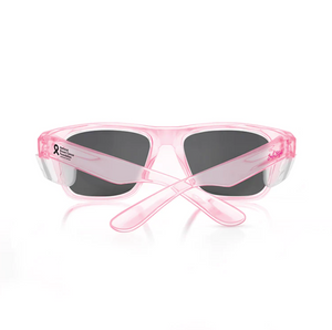 The SafeStyle Fusions Pink Frame Polarised Lens sunglasses feature transparent pink polycarbonate frames, black polarised lenses, and a left arm adorned with a small black ribbon plus "Breast Cancer Awareness Month" text. Shown from the back.