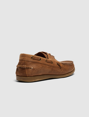The Rodd & Gunn Gordons Bay Boat Shoe in brown leather is shown from the back, highlighting its moccasin-style stitching, side eyelets with laces, and a durable rubber outsole against a light gray background.