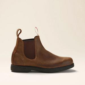 The Rossi Booma 607 Elastic Sided Boot is a brown Chelsea work boot made from Full Grain Australian Leather, showcasing a smooth finish and complemented by black elastic side panels and pull tabs at the front and back. It features a slip-resistant black sole with "Ross" embossed near the heel, all set against a neutral, light beige background.