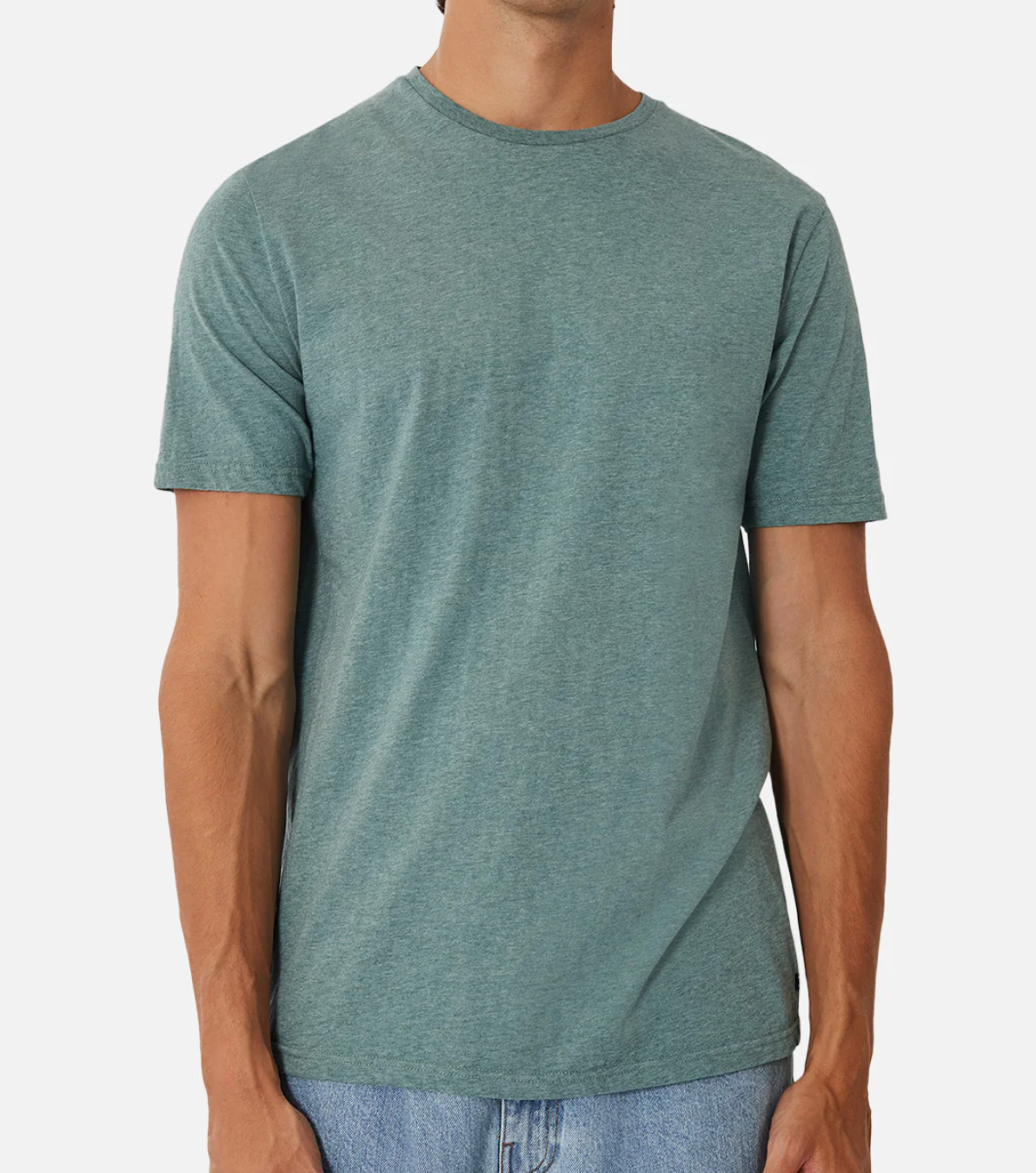 Someone models the Industrie The Basic Crew Tee in light blue-green, made from 100% cotton, with light blue jeans against a plain white background. The focus is on this everyday staple as the person's face remains unseen.