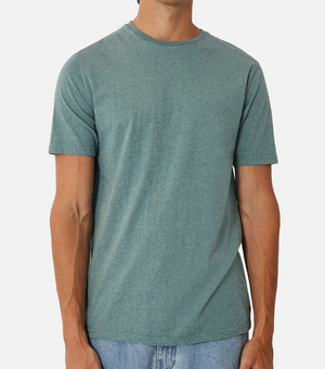 Someone models the Industrie The Basic Crew Tee in light blue-green, made from 100% cotton, with light blue jeans against a plain white background. The focus is on this everyday staple as the person's face remains unseen.