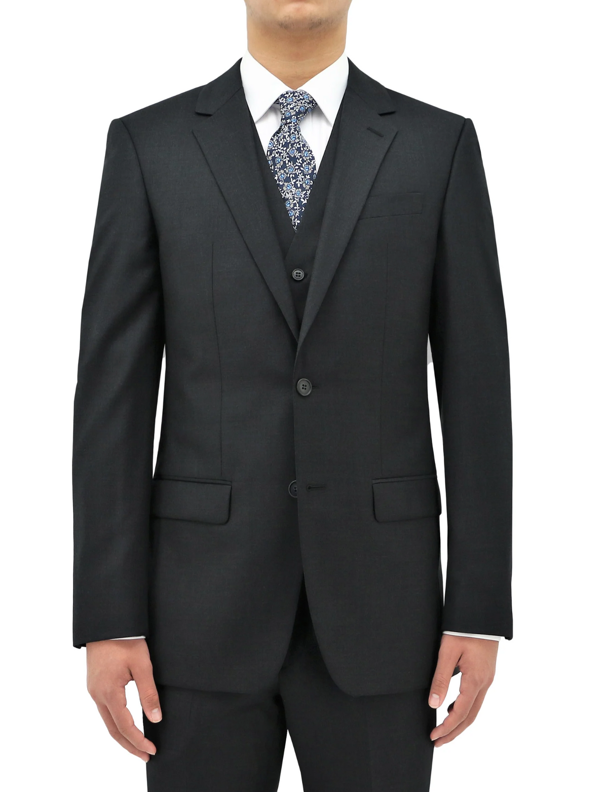 A person is standing with arms by their sides, dressed in a dark grey Boston Michel Jacket paired with a matching vest. They are also wearing a white dress shirt and a patterned tie. The comfort fit suit jacket features two buttons and the background is plain white.