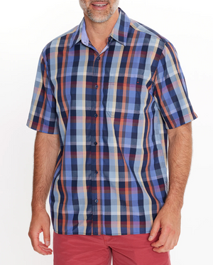 A man wears the Breakaway Rome Bamboo Blend Shirt, a comfy short-sleeved multicolored plaid button-up in shades of blue, red, and beige. He pairs it with red shorts against a plain white background.