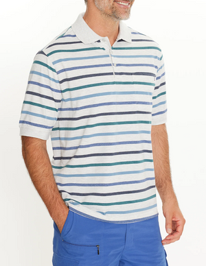 A person wearing the Breakaway Ozi Kinnersly Polo with horizontal blue, green, and gray stripes is paired with blue pants and has hands in pockets. The shirt features a rib knit collar for added comfort against a plain white background.
