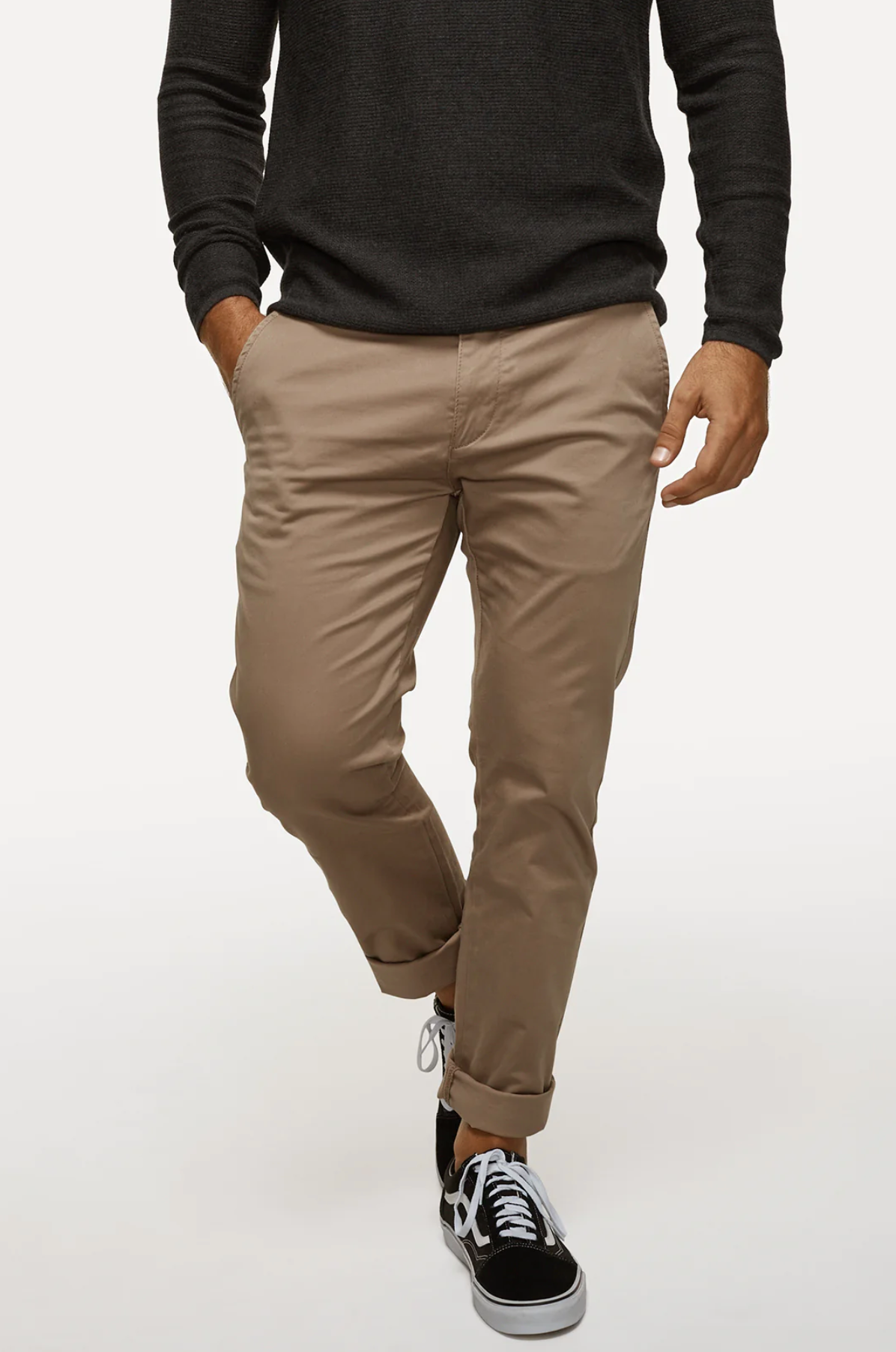 A person is sporting a black sweater and beige Industrie The Regular Cuba Chino Pants, which are crafted from stretch cotton for added comfort and feature a sleek fit, with their hands in the pockets. They are also wearing black and white sneakers against a plain, neutral background.