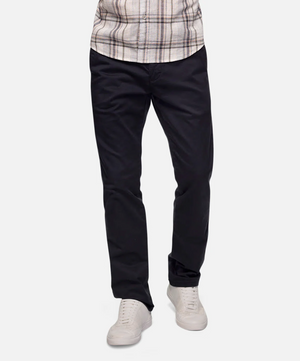A person is wearing a pair of Industrie The Regular Cuba Chino Pants in black with side pockets, a plaid shirt, and white sneakers. The image shows from the waist down, focusing on the clothing and footwear against a plain white background.