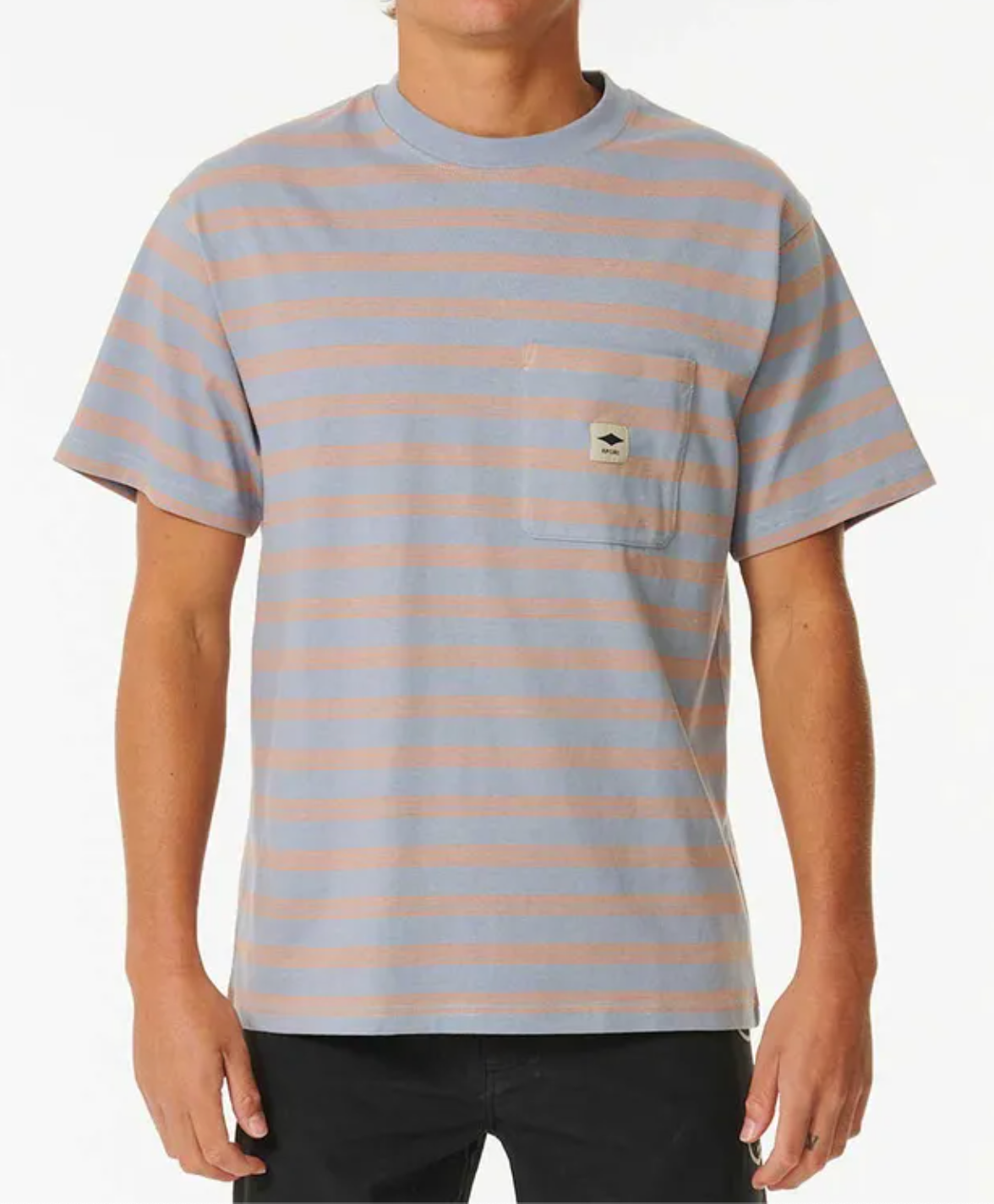 A person is wearing the Rip Curl Quality Surf Products Stripe Tee, which is short-sleeved with blue and pink stripes, a small left chest pocket featuring a patch, paired with black pants. The background is plain white.