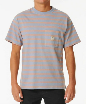 A person is wearing the Rip Curl Quality Surf Products Stripe Tee, which is short-sleeved with blue and pink stripes, a small left chest pocket featuring a patch, paired with black pants. The background is plain white.