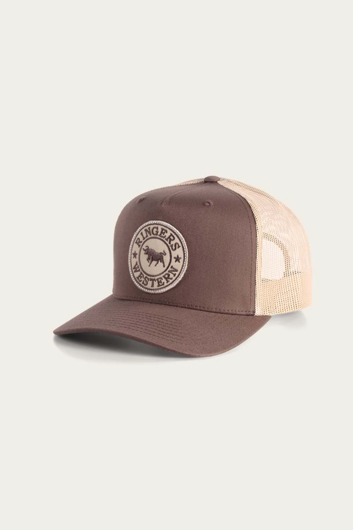 The Ringers Western Signature Bull Trucker Cap features a brown and beige cotton twill front with a round logo patch, a mesh back for ventilation, and classic trucker styling.