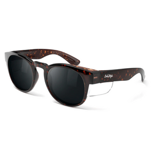 The SafeStyle Cruisers Brown Tort Frame Polarised Lens features round polycarbonate frames with a speckled brown and black tortoiseshell pattern, dark polarised lenses, silver accents, and a white signature logo on the left arm.