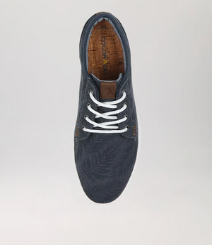 A top view of the Colorado Albatross Canvas Sneaker, showcasing a dark blue leaf-patterned design. It features white laces and a brown insole, offering a wide fit for comfort against a plain light grey background.
