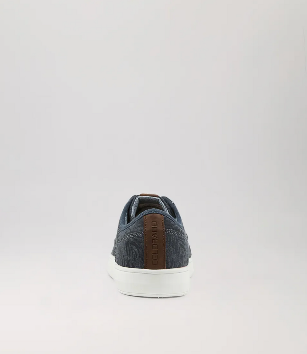 The single Colorado Albatross Canvas Sneaker, shown from the rear on a gray background, features a denim-like texture with a brown leather heel accent and white sole. It includes a memory foam inner sole for enhanced comfort.