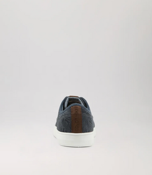 The single Colorado Albatross Canvas Sneaker, shown from the rear on a gray background, features a denim-like texture with a brown leather heel accent and white sole. It includes a memory foam inner sole for enhanced comfort.