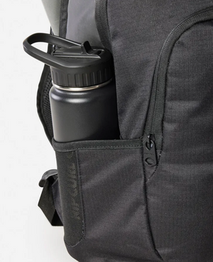 A Rip Curl Ozone Icons 30L Backpack in black features a side pocket holding a matte black water bottle with a handle. The partially open zipper reveals subtly textured fabric and organized compartments for essentials.