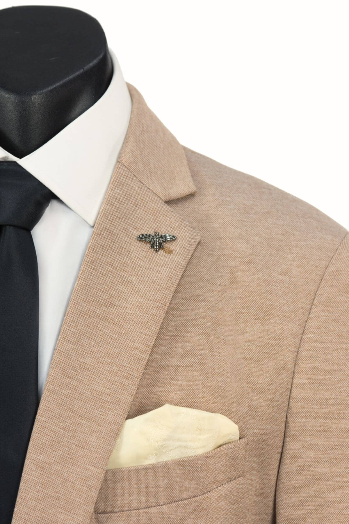 Close-up of a beige Scuzzatti Stretch Slim Fit Sports Jacket with a single-button notch lapel, white shirt, black tie, cream pocket square, and bee lapel pin. Made from lightweight stretch fabric. Plain white background.
