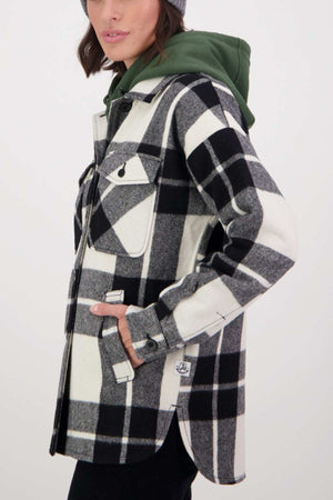 A person wearing a Swanndri Anchorage v2 Wool Shirt Jacket in a black and white checkered pattern, featuring large buttons and a green hood. The jacket includes chest pockets with flaps, a drop shoulder design, and welt hip pockets. The person is slightly turned to the side, revealing a portion of their face.